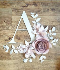 paper flowers and leaves are arranged in the shape of a letter on a wooden surface