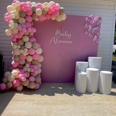 a pink and white baby shower with balloons on the wall next to toilet paper rolls