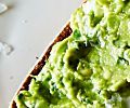 a toasted bread topped with guacamole on top of a white plate