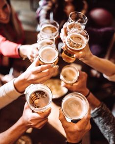 many people are toasting with beer glasses