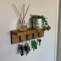 a wooden shelf with key hooks and plants on it, hanging from the wall next to a door