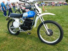 a blue and white dirt bike parked on top of a lush green grass covered field