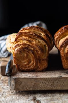 two loaves of bread sitting on top of a wooden cutting board