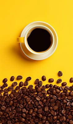 a cup of coffee sitting on top of a pile of coffee beans next to a yellow background