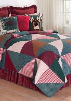 a bed with red and green bedspread, pillows and blankets on top of it