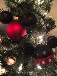 a christmas tree with mickey mouse ornaments hanging from it's top and red ornament