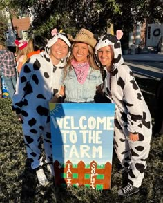 three people in costumes posing with a sign that says welcome to the farm on it