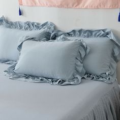 a bed with blue ruffled sheets and two pillow cases on it's headboard