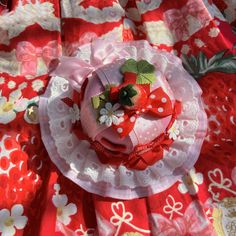 a red and white plate topped with a pink flower on top of a table cloth