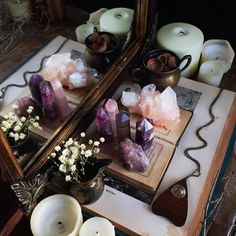 candles and crystals are on a table in front of a mirror