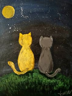 two cats sitting in the grass watching the moon