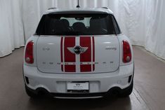 the back end of a small white car with red and white stripes on it's side