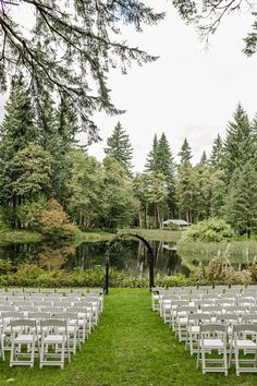 rows of white chairs set up in front of a pond for an outdoor wedding ceremony