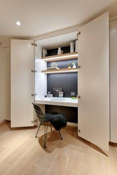 an empty room with a desk, chair and shelves on the wall in it's corner