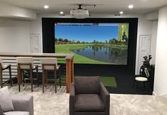 a room with chairs and a television in the middle of it that has a golf simulator on the wall