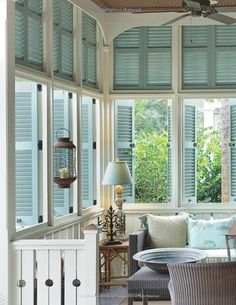 a living room filled with furniture and windows covered in shuttered glass doors, next to a wooden table