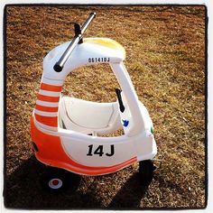 an orange and white toy car sitting in the grass