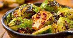 a bowl filled with brussel sprouts on top of a wooden table