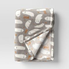 a blanket with ghost faces on it is folded in front of a white wall and grey background