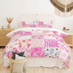 a bed with pink and white flowers on it in a room next to a wicker basket