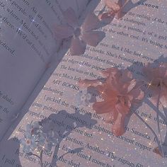 an open book with pink flowers on it and sparkles in the backround