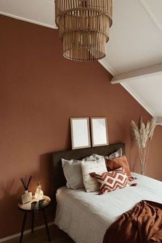 a bedroom with brown walls and white bedding, two framed pictures on the wall