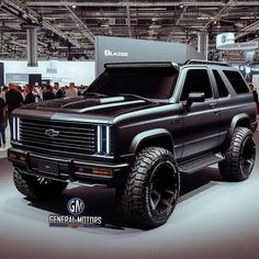 a black truck is on display in a showroom with people looking at the vehicles