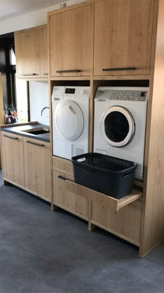 a washer and dryer in a room with wooden cabinets on either side of the washer and dryer