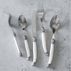 four silverware with spoons, forks and knives on a gray table top next to each other