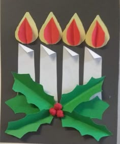 an origami card with candles and holly leaves