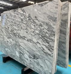 large marble slabs are being displayed in a warehouse with blue flooring and white walls