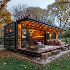 a house made out of shipping containers with lights on the roof and patio furniture in front