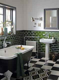 a black and white checkered floor bathroom with green tiles on the walls, an old bathtub in the middle