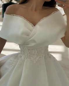 a woman in a white wedding dress holding a cell phone