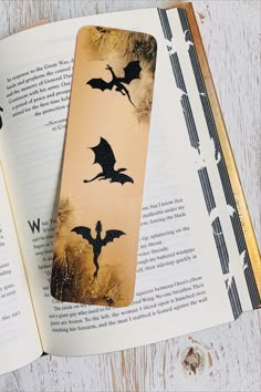 an open book with some black bats on it and another bookmark in the shape of a bat