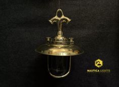 an antique brass hanging light fixture on a black background with the caption nautical lights