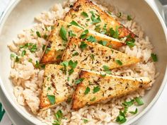 a bowl filled with rice and pieces of fried tofu on top of it, garnished with parsley