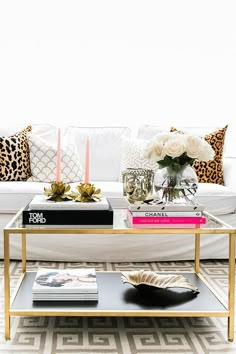 a living room with a couch, coffee table and books on the tables in front of it