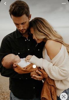 a man and woman holding a baby in their arms