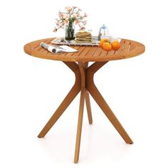 a wooden table with plates and utensils on it, next to flowers in a vase