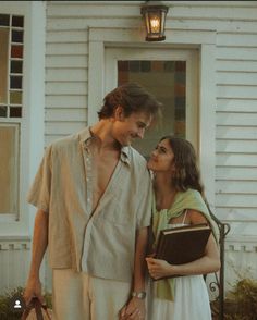 a young man and woman standing in front of a house