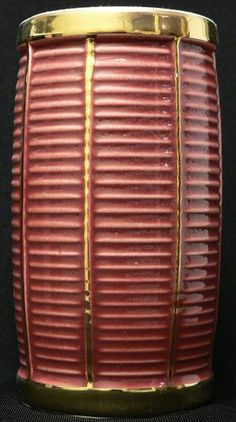 a red and gold vase sitting on top of a black table