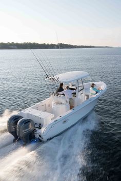 two people on a white boat in the water with their fishing rods out and one person driving behind them