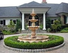 a car parked in front of a large house with a water fountain on the driveway