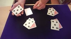 a person is playing cards on a table with their hands in the air and holding them up