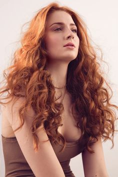 a woman with long red hair sitting down