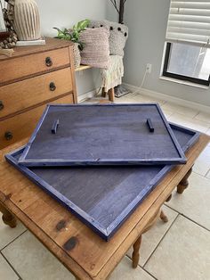 two blue trays sitting on top of a wooden table next to a dresser and chair