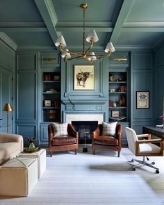 a living room filled with furniture and a fire place under a chandelier in front of a fireplace