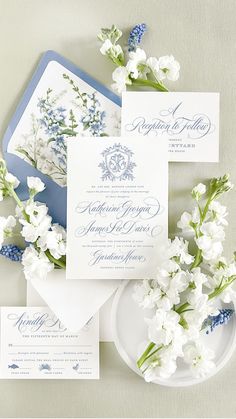 the wedding stationery is laid out on top of each other, with blue and white flowers