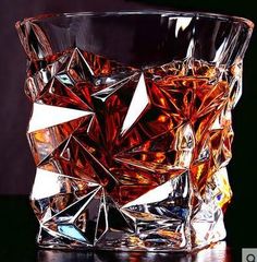 a glass filled with liquid sitting on top of a wooden table next to a black background